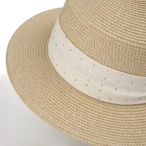 Detailed close-up of straw hat with white mesh band and shimmering rhinestones