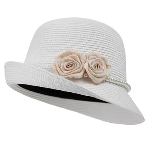 Detailed view of handwoven white straw hat with satin roses and pearl bead decorations