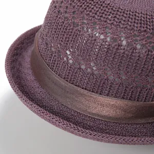 Close-up of deep purple knit cloche hat showing mesh texture and shiny brown ribbon