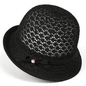 Detail of black woven summer hat featuring a ribbon bow with pearl and rhinestone accents