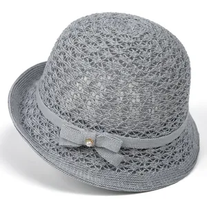 Detail of grey woven sun hat featuring a mesh crown and pearl bow decoration