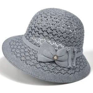 Detail of grey hollow-weave sun hat featuring a delicate bow and pearl ornament