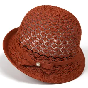 Close-up of rust red woven sun hat featuring a pearl rhinestone bow and knit texture
