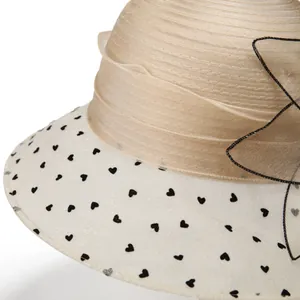 Detail of pleated khaki crown and white brim with black heart patterns and mesh bow