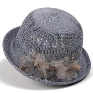 Close-up of elegant grey knit sun hat with floral mesh details and sparkling rhinestones