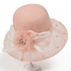 Détail d'un chapeau de soleil en organza rose avec fleur élégante, perles et strass