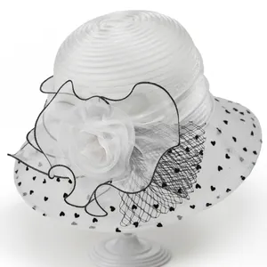 Detailed view of white organza sun hat with large floral decor and black heart patterns