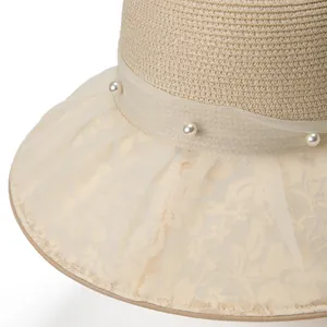 Dettaglio di un cappello di paglia elegante con pizzo delicato e perle decorative