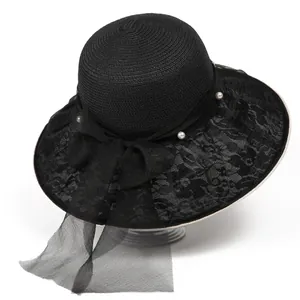 Dettaglio cappello di paglia nero con tesa in pizzo, perle e grande fiocco in rete