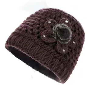 Primer plano detallado de un gorro de punto violeta oscuro con flores 3D y strass