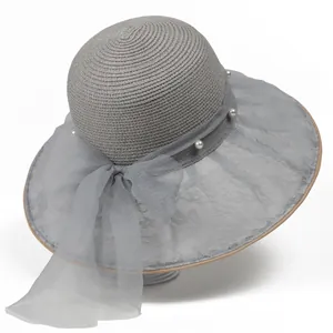 Dettaglio cappello di paglia grigio con fiocco in rete trasparente e perle bianche