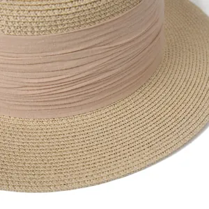 Détail de la texture en paille tressée et ruban plissé rose poudré sur ce chapeau