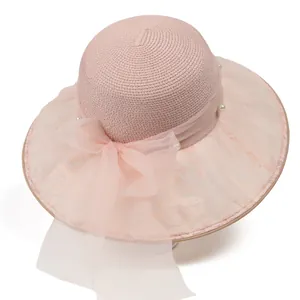 Dettaglio di cappello di paglia rosa con fiocco in organza e perle bianche per l'estate