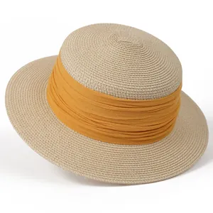 Détail d'un chapeau de paille beige avec un ruban décoratif en tissu plissé jaune vif