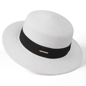 Detail of a beige straw hat with black ribbon and a gold Hi Crown metal plaque