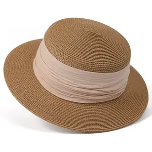 Détail d'un chapeau de paille marron avec tissage fin et ruban élégant en mousseline rose