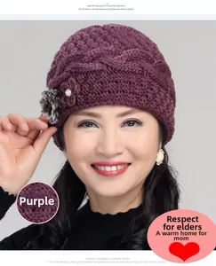 Detail of purple knitted wool hat with crochet flower, pearl and faux fur pompom accents