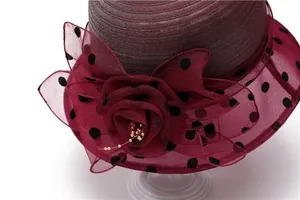 Detail of burgundy sun hat with polka dot organza flower and pearl accent