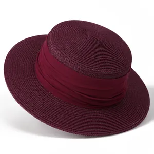 Gros plan détaillé d'un chapeau de paille bordeaux avec texture tressée et ruban élégant
