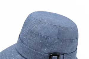 Close-up of light blue cotton sun hat featuring white polka dots and black square buckle