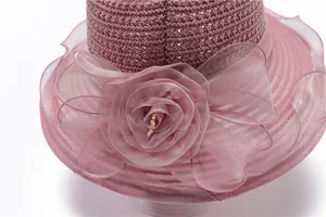 Close-up of pink organza flower with pearl on a textured straw sun hat for women