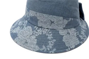 Detail of dark blue sun hat featuring white floral patterns and denim texture