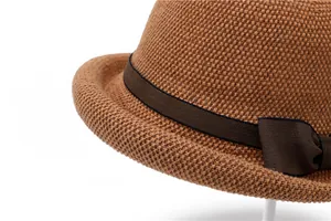 Close-up of brown woven sun hat featuring dense texture and decorative ribbon bow