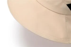 Close-up detail of smooth stitching and black ribbon on beige wide brim sun hat