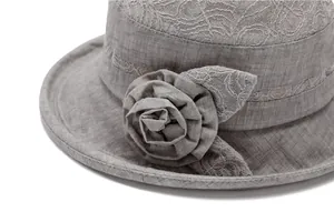 Detailed close-up of grey sun hat featuring a 3D fabric flower and delicate lace trim