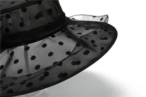 Detailed close-up of black organza sun hat with polka dots and layered brim texture