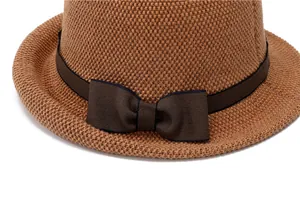 Detailed macro view of woven straw sun hat featuring a classic brown bow ribbon detail