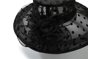 Close-up of black organza sun hat with white polka dots and large decorative floral layer