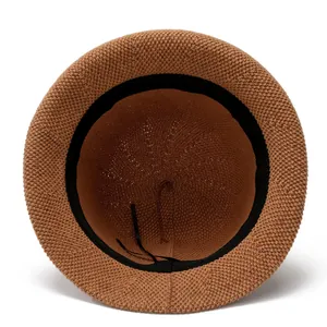 Internal view of brown straw hat featuring black sweatband and adjustable drawstring