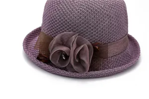 Détail d'un chapeau de soleil en maille avec fleur en résille violette et ruban satiné