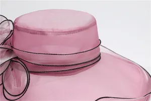 Detail of light pink organza sun hat with black stitched edges and floral decoration
