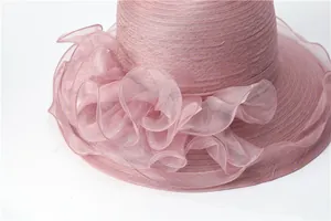 Détail d'une fleur élégante en organza rose sur un chapeau de soleil tissé femme