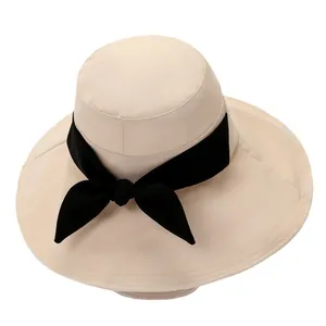 Elegant beige sun hat for women with wide brim and large black decorative bow