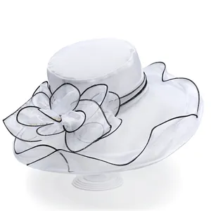 Detail of white organza sun hat featuring large mesh flower with pearl and black outlines