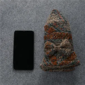 Dettaglio cappello in lana a maglia spessa multicolore con fiocco laterale e quadri