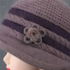Detalle de gorro de invierno de punto con adorno floral y pompón de pelo sintético