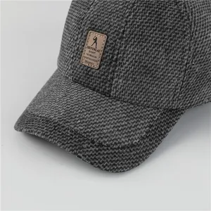 Dettaglio cappello invernale da uomo con trama a maglia grigia e patch in pelle marrone