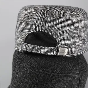 Detail of grey plaid flat top cap featuring tweed texture and adjustable silver metal buckle