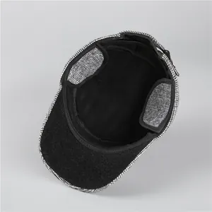 Detail of tweed flat cap featuring integrated ear flaps and warm black fleece lining