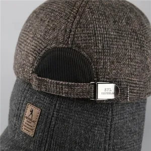 Macro detail of plaid winter cap showing adjustable metal buckle and leather brand tag