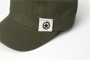 Detail van olijfgroene platte pet met stiksels en ster-logo label op de zijkant