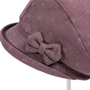Detailed close-up of dark reddish-brown fabric sun hat with elegant bow and white patterns
