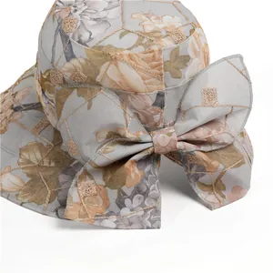 Close-up of elegant floral sun hat with large bow detail and golden grid pattern mesh