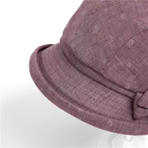 Detail view of burgundy fabric bucket hat with geometric patterns and bow decoration