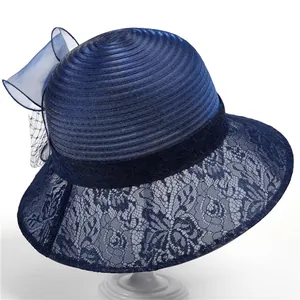 Détail de chapeau bleu marine avec dentelle florale et nœud en organza sur support blanc