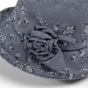 Dettaglio cappello sole blu-grigio con stampa floreale e decorazione a rosa in 3D
